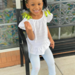 Berkeley Hermès Roberts smiling in white outfit with yellow braided hair