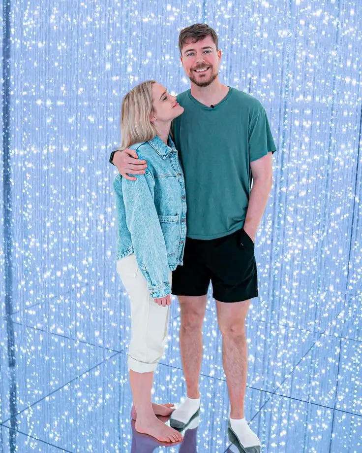 MrBeast Jimmy Donaldson embracing his girlfriend Thea Booysen in front of a sparkling light backdrop